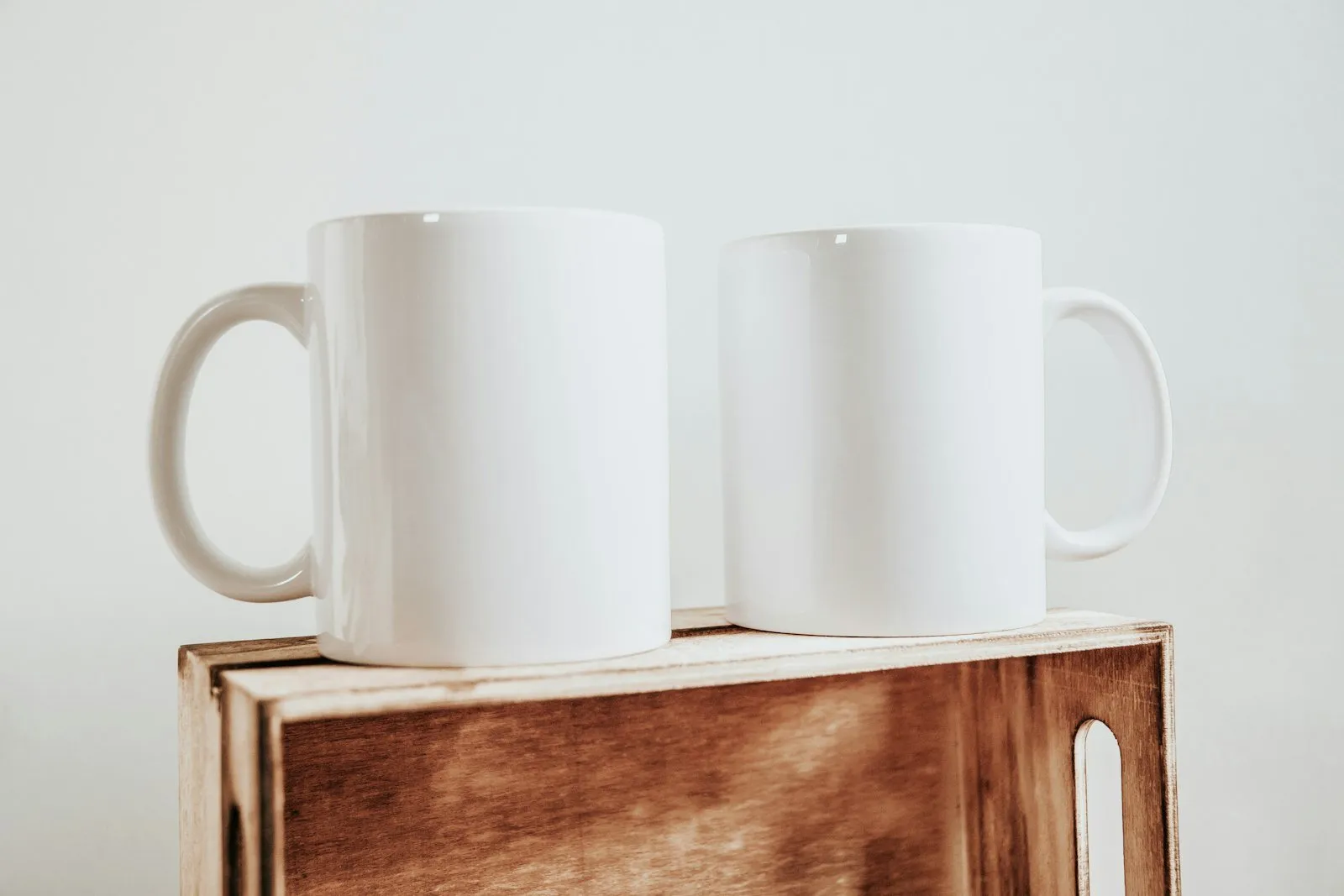 Two white mugs on a wooden shelf