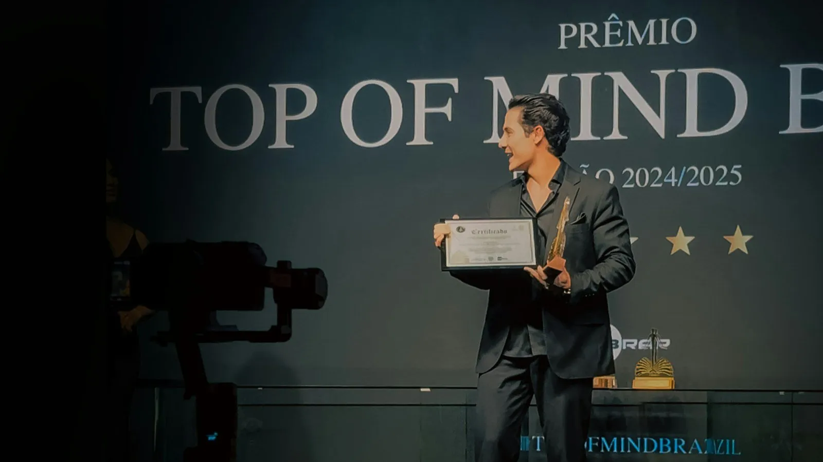 A man in a suit accepts an award on stage