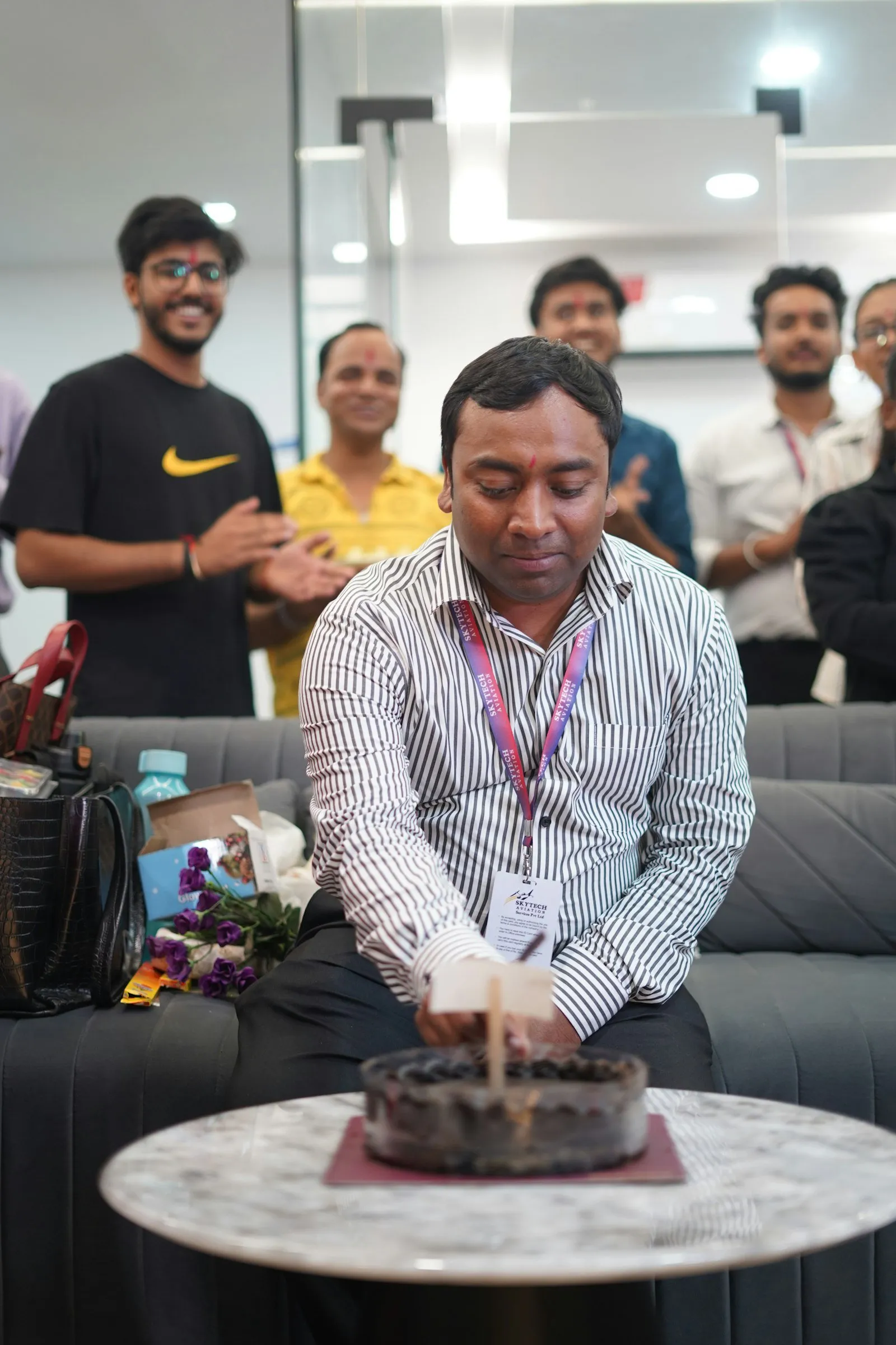 A man cuts a cake while colleagues clap