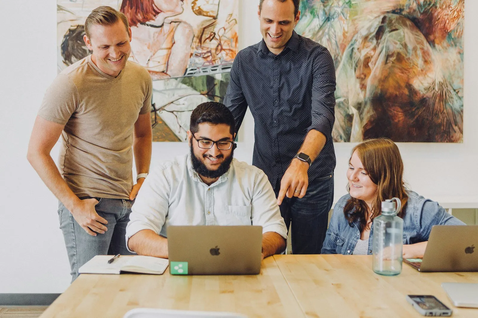 Four coworkers smiling around a laptop