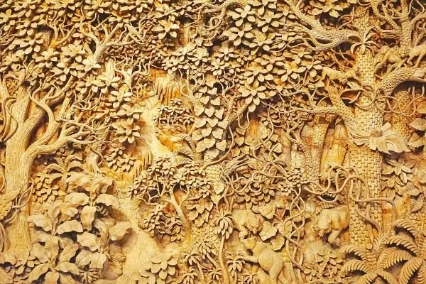 A dense forest of twisting trees and layered foliage, carved in golden sandstone tones