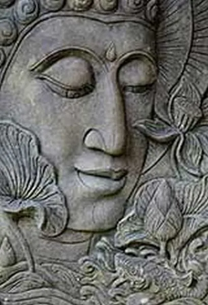 A serene Buddha face with closed eyes emerges from carved leaves and lotus forms in cool grey stone