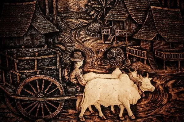 A farmer leads two white bullocks and a cart along a village path, in rich sepia relief
