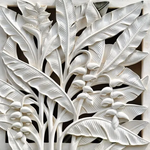 Broad banana leaves and hanging heliconia flowers in a crisp, pure white sculpted relief