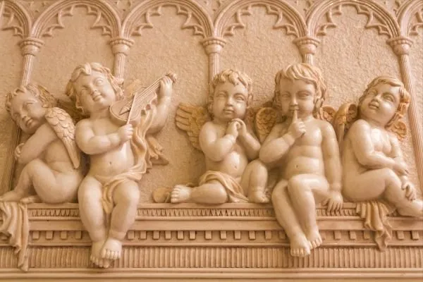 Five chubby cherubs sit on a classical ledge beneath arches, one playing a violin, in soft peach relief