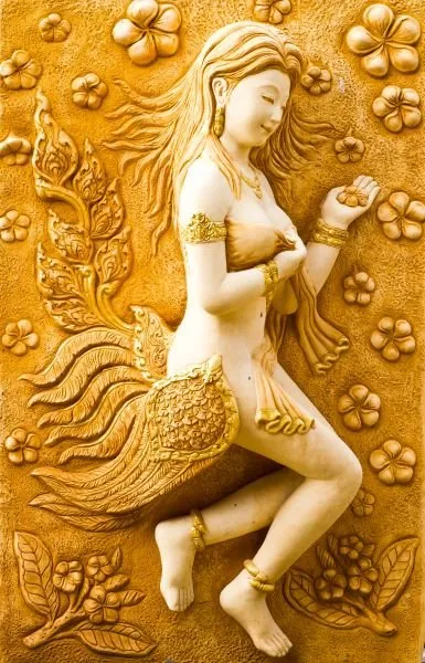 A flying celestial maiden with a feathered tail, rendered in ivory against a glowing amber relief
