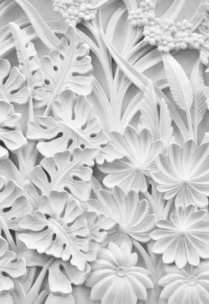 Monstera leaves, ferns and starry flowers climb a tall panel in crisp white sculpted relief