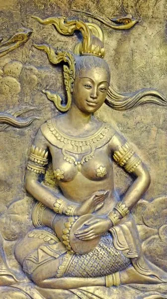 A seated celestial musician cradles a small drum, crowned and jewelled in burnished gold
