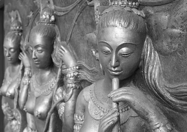 A line of celestial maidens playing flutes, in cool silver-grey relief