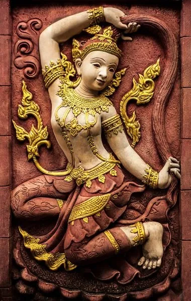 A crowned temple dancer strikes a graceful pose in gold and cream against a deep crimson ground