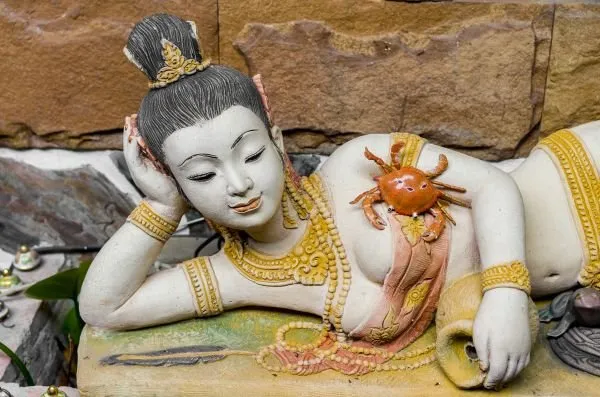 A painted figure of a crowned maiden reclining on one elbow, a small red crab resting at her side