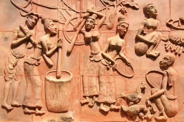 Villagers pound grain, play music and dance in a lively terracotta-orange relief