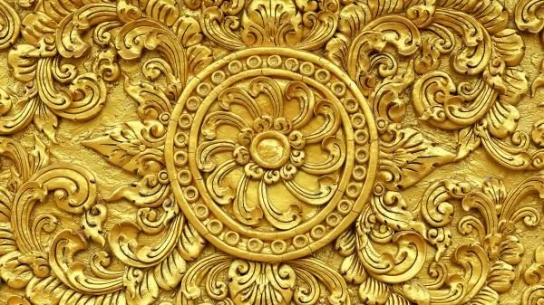 A radiant gold medallion of petals and scrolling flourishes, in gleaming carved relief