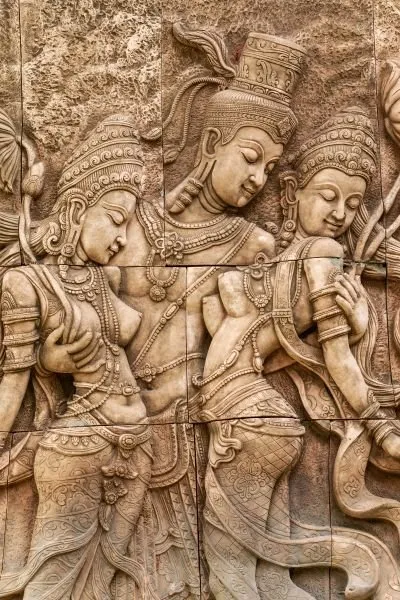 Three crowned figures lean together in a tall, tiled sandstone relief