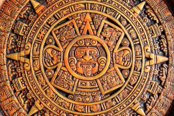 The Aztec sun stone of rings, glyphs and a central face, in rich orange-brown relief