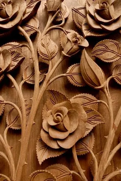 Open roses, buds and leaves climb a tall panel in warm, hand-carved wood tones