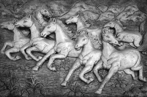 A herd of silver-white horses gallops past distant hills, in a cool monochrome relief