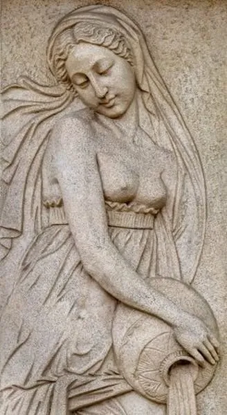 A veiled maiden pours water from a pot, carved in soft taupe stone