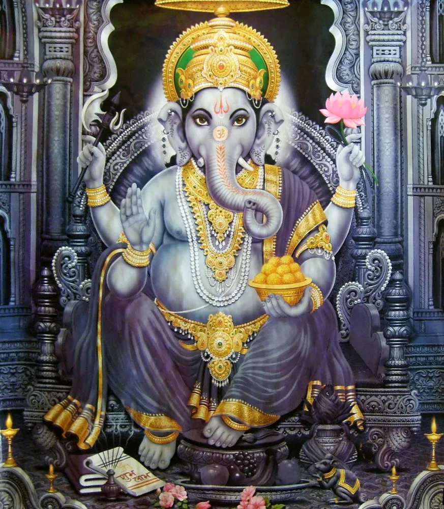 A blue-grey Ganesha adorned in gold, seated within an ornate carved temple niche